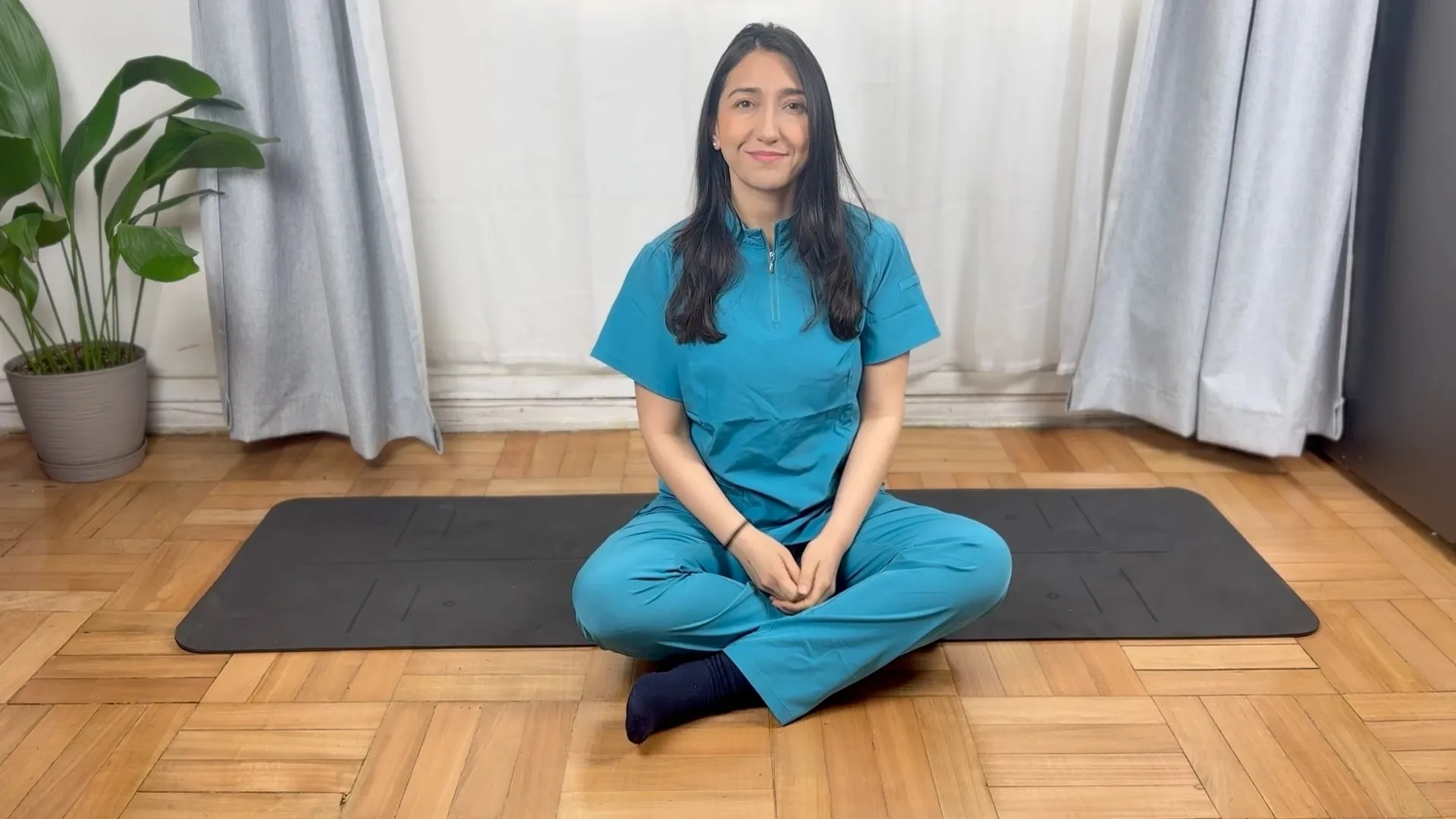 Isabel Valdés, physiotherapist, sitting on an exercise mat on the floor, ready to begin a gentle class